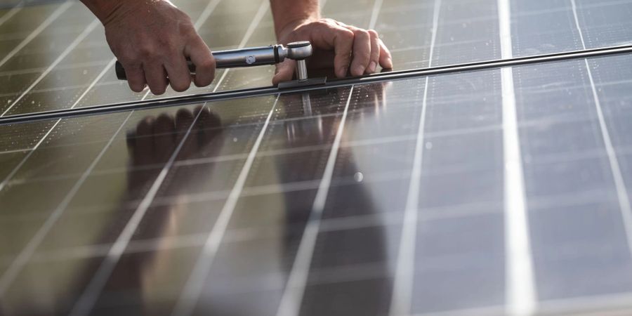 Ein Arbeiter montiert Photovoltaikmodule auf dem Dach eines Wohnhauses. Das Comeback der Solarbranche in Deutschland lockt Investoren an.