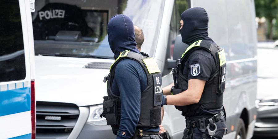 Polizisten führen einen Mann ab. Mit einer  Razzia ist die Polizei in Berlin gegen den organisierten Drogenhandel vorgegangen.