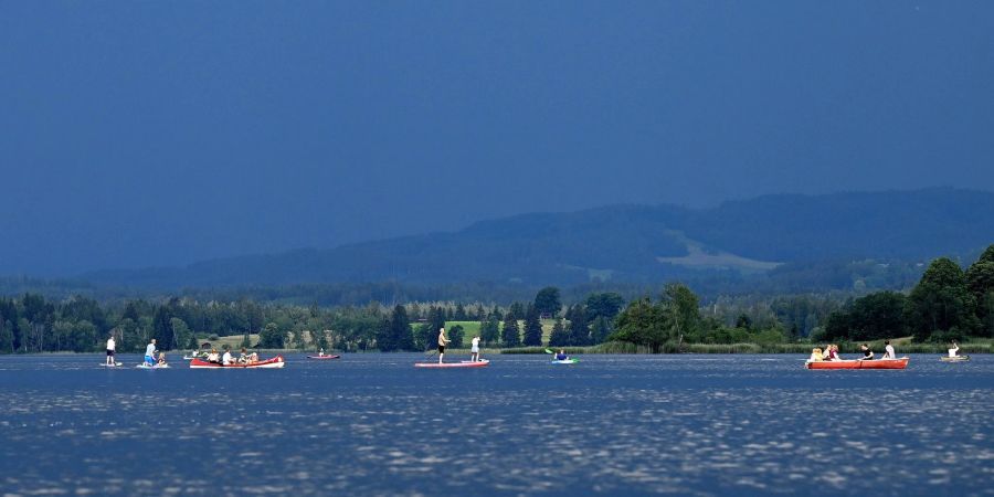 Ausflügler auf dem Wasser flüchten vor einer herannahenden Gewitterfront über dem Staffelsee in Bayern.