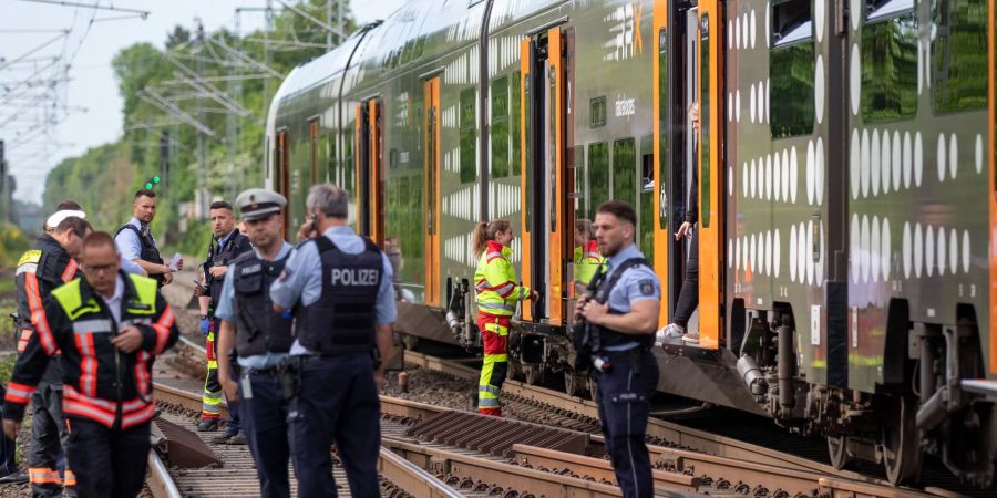 Polizisten stehen vor der Regionalbahn, in der sich die Attacken ereigneten.