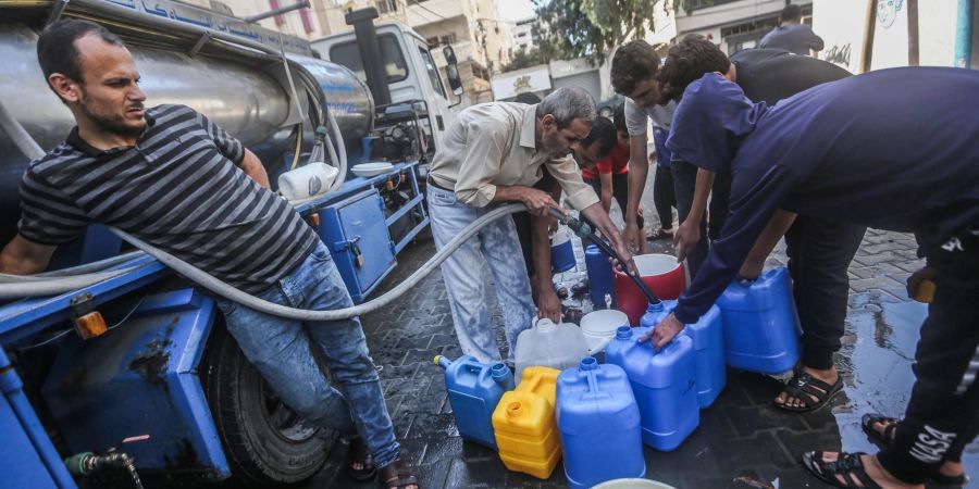 Palästinenser füllen Behälter mit Trinkwasser aus einem Wasserverteilungsfahrzeug auf.