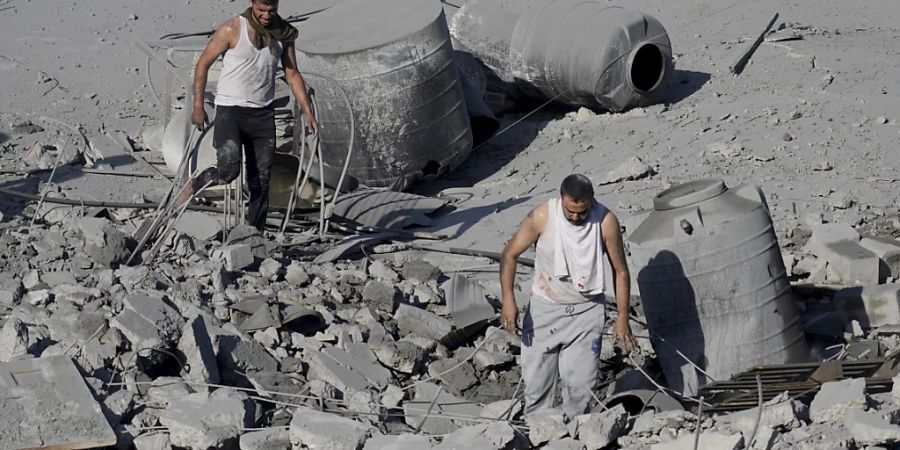 Zwei Männer laufen nach einem israelischen Angriff im Gazastreifen durch die Trümmer. Foto: Hatem Moussa/AP/dpa