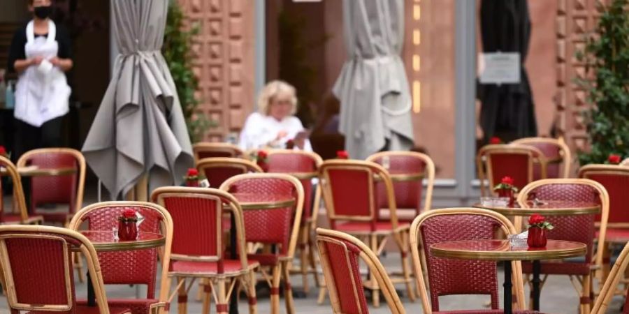 Viele freie Tische vor einem Café in Frankfurt. Foto: Arne Dedert/dpa