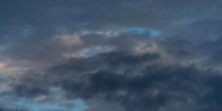 Dunkle Wolken zeichnen sich am Himmel nach Sonnenaufgang ab. Foto: Lino Mirgeler/dpa