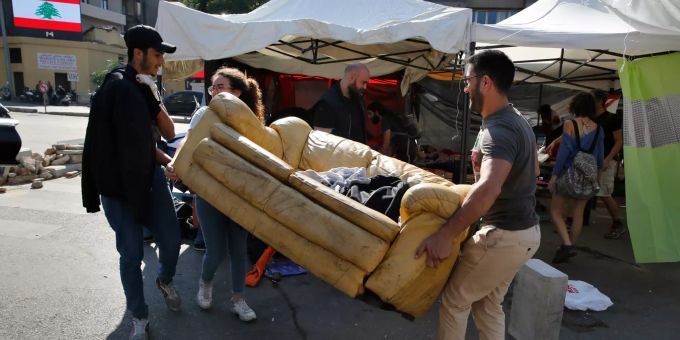 Regierungskritische Demonstranten tragen ein Sofa von der Strasse weg. Nach dem Rücktritt von Ministerpräsident Hariri haben die Demonstranten mit dem Abbau von Barrikaden begonnen und zentrale Straßen in Beirut wieder freigegeben. libanon
