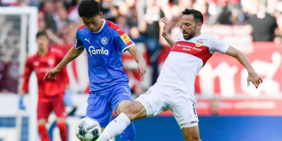VfB-Profi versucht Kiels Torschützen Jae Sung Lee (l) zu stoppen. Foto: Tom Weller/dpa