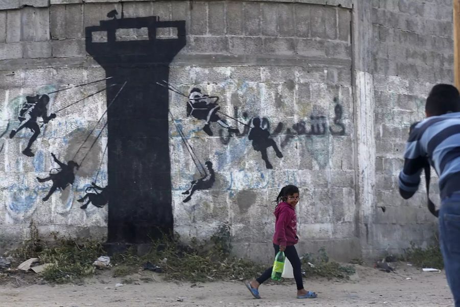 Ein Wachturm dient in einem Banksy-Kunstwerk als Kinderkarussel.