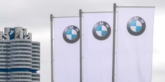 Flaggen mit dem Logo des Münchner Autobauers BMW wehen vor der Olympiahalle. Foto: Sina Schuldt/dpa rendite