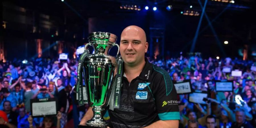 Holte sich in Göttingen den EM-Pokal im Darts: Rob Cross. Foto: Swen Pförtner/dpa