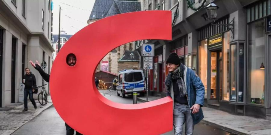 Ein Aktivist geht mit einem nachgebauten Buchstaben C aus dem Logo der CDU vor der Nikolaikirche in Leipzig über eine Strasse. Foto: Hendrik Schmidt/dpa