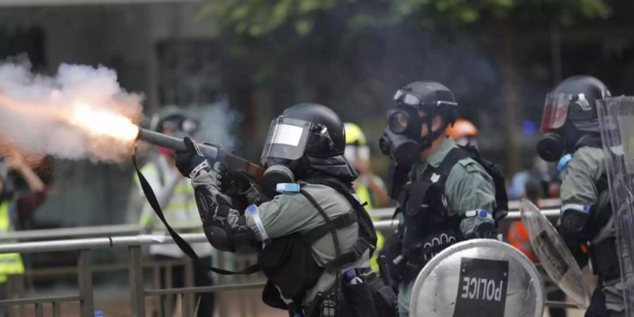 Ein Polizist setzt Tränengas gegen Demonstranten ein. Foto: Vincent Thian/AP