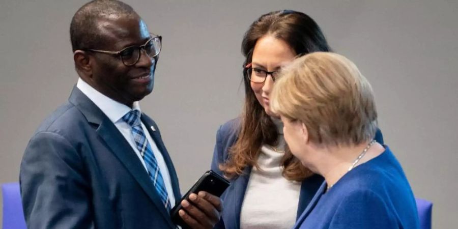 Bundeskanzlerin Angela Merkel (CDU) stellt sich hinter den SPD-Bundestagsabgeordneten Karamba Diaby (li), nachdem dessen Bürgerbüro angegriffen wurde. Foto: Kay Nietfeld/dpa