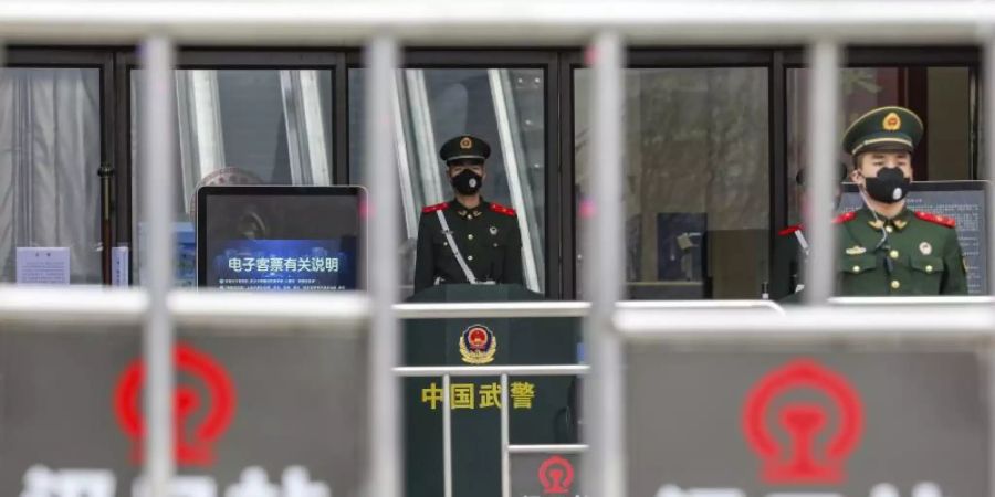 Sicherheitskräfte stehen mit Mundschutz vor dem geschlossenen Bahnhof Hankou in Wuhan. Foto: --/CHINATOPIX/AP/dpa