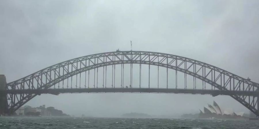 Winde peitschen das Wasser auf: Sydneys Harbour Bridge versinkt im Regenschleier. Foto: Bai Xuefei/XinHua/dpa