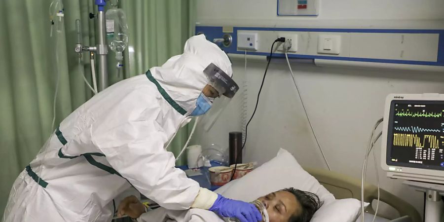 Eine Pflegefachfrau in einem Spital in der chinesischen Stadt Wuhan gibt einem am neuartigen Coronavirus erkrankten Patienten Wasser ein.