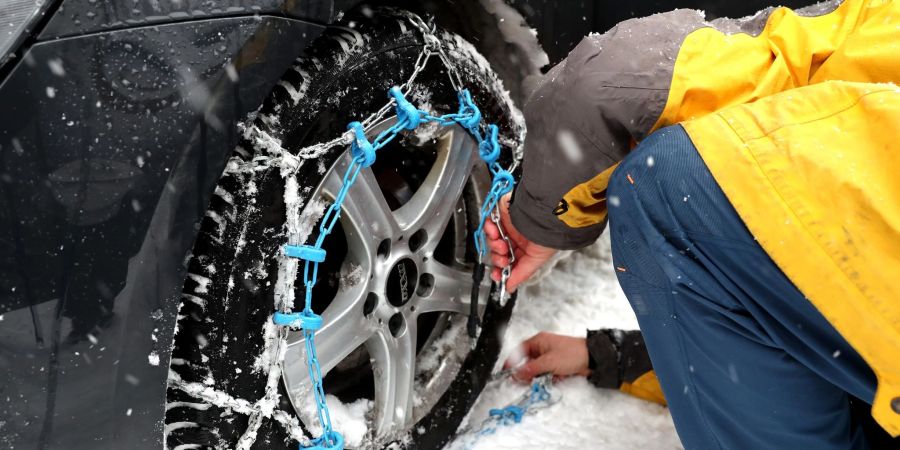 Mit geübter Hand: Das Anlegen von Schneeketten üben Autofahrer besser vor dem Ernstfall. Um die Hände vor Kälte und kleinen Verletzungen zu schützen, sollte man zudem Handschuhe nutzen.