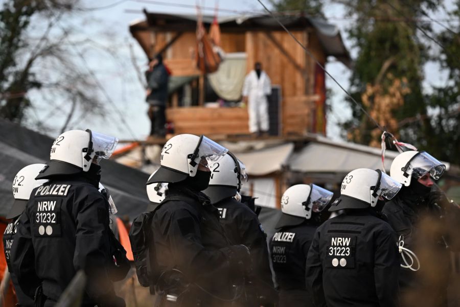 Eine Gruppe Polizisten steht bei der Räumung von Lützerath vor Bretterhütten, die von Aktivisten und Demonstranten gebaut worden waren. Der Energiekonzern RWE will die unter Lützerath liegende Kohle abbaggern - dafür soll der Weiler auf dem Gebiet der Stadt Erkelenz am Braunkohletagebau Garzweiler II abgerissen werden.