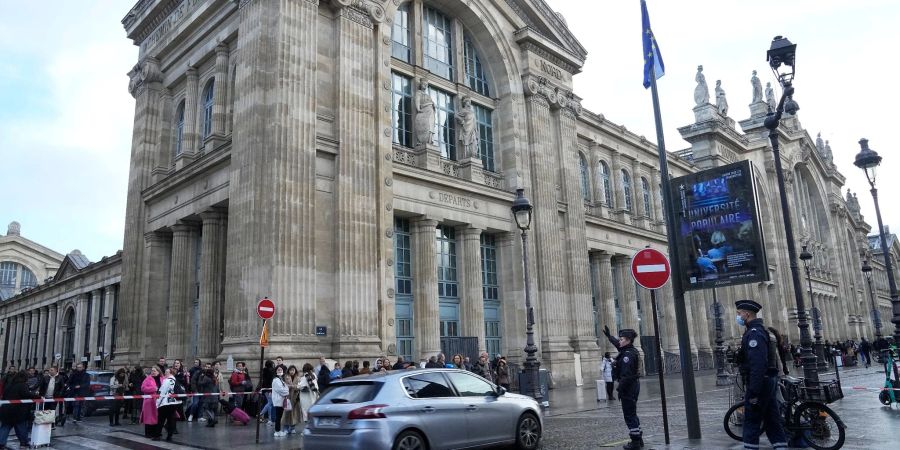 Menschen warten hinter einer Polizeiabsperrung vor dem Bahnhof Gare du Nord in Paris.