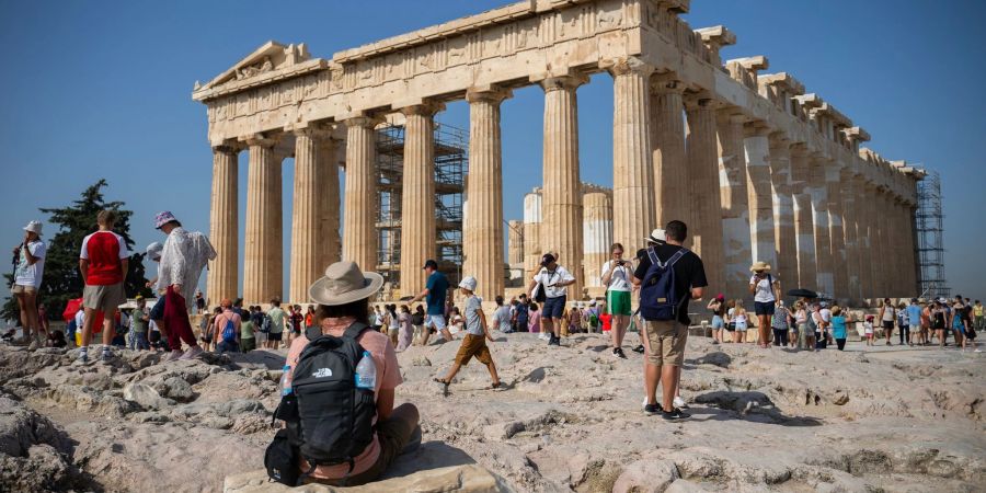 Touristen in Athen gehen an einem heissen Tag bei ihrem Besuch des Parthenon-Tempels auf dem Akropolis-Hügel.