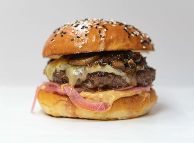 Manfred Zimmers Pilzburger kommen mit Cheddar und roten Zwiebeln. Cheeseburger