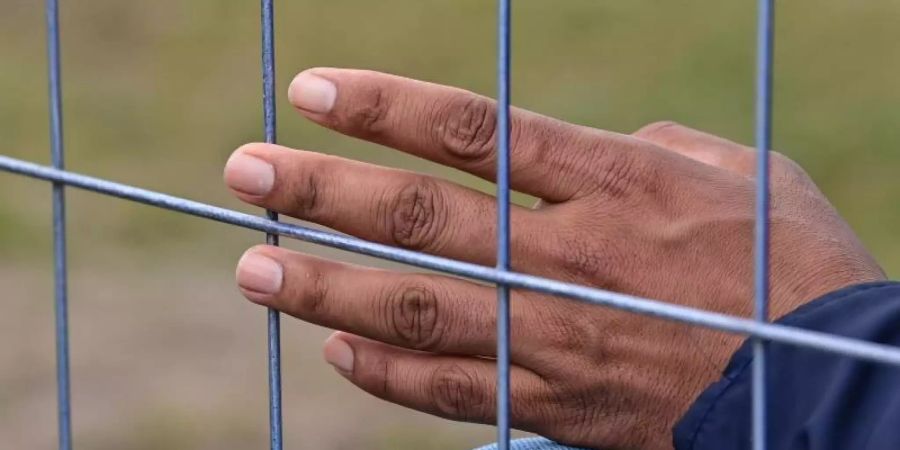 Die Hand eines Flüchtlings am Zaun einer Erstaufnahmeeinrichtung für Asylbewerber. Foto: Patrick Pleul/dpa-Zentralbild/ZB
