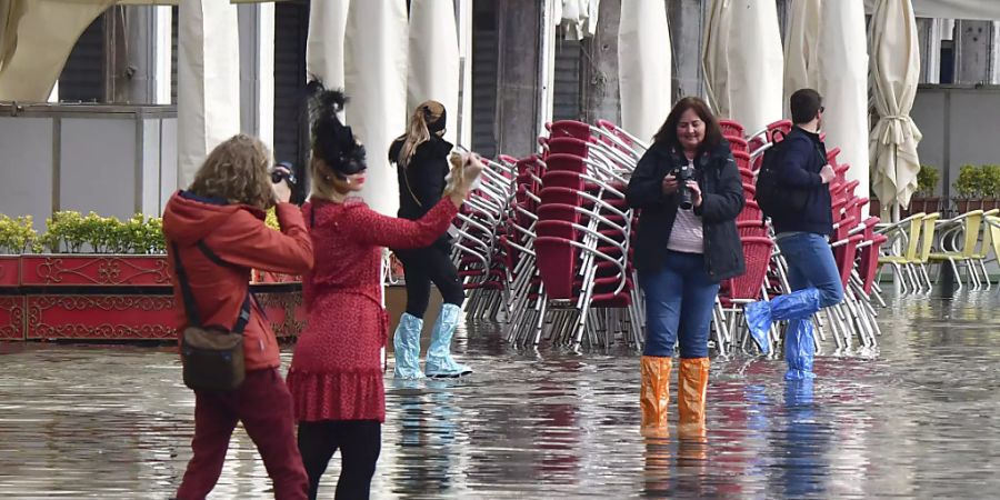 Menschen auf dem überfluteten Markusplatz. Wegen Unwettern und starker Winde droht der norditalienischen Lagunenstadt Hochwasser. Foto: Matteo Tagliapietra/LaPresse/dpa