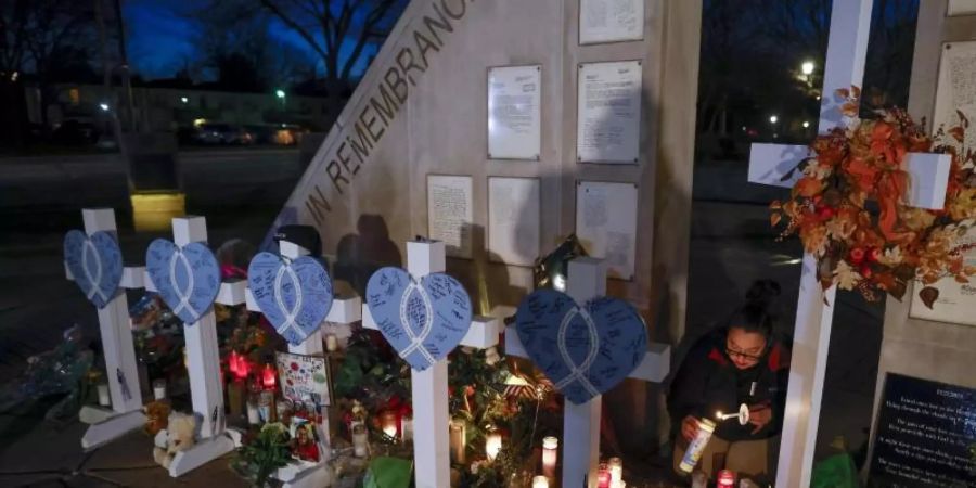 Eine Frau zündet Kerzen an einer Gedenkstätte im Veteran's Park für die Opfer an, nachdem ein Geländewagen am Sonntag in eine Weihnachtsparade gerast war, bei der mehrere Menschen getötet und Dutzende verletzt wurden. Foto: Jeffrey Phelps/AP/dpa