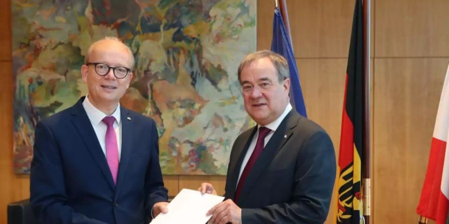 André Kuper (l) überreicht Armin Laschet die Urkunde über die Beendigung des Amtes als Ministerpräsident. Foto: Bernd Schälte/Landtag NRW/dpa