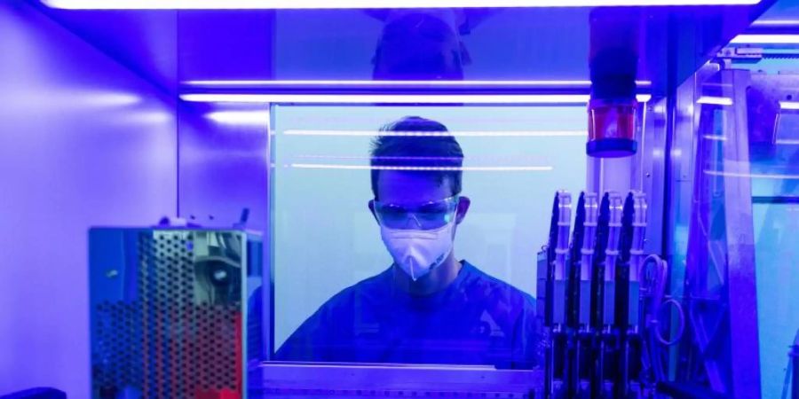 Ein Laborant untersucht in einem Labor an einem PCR-Vollautomaten Corona-Abstriche. Foto: Boris Roessler/dpa