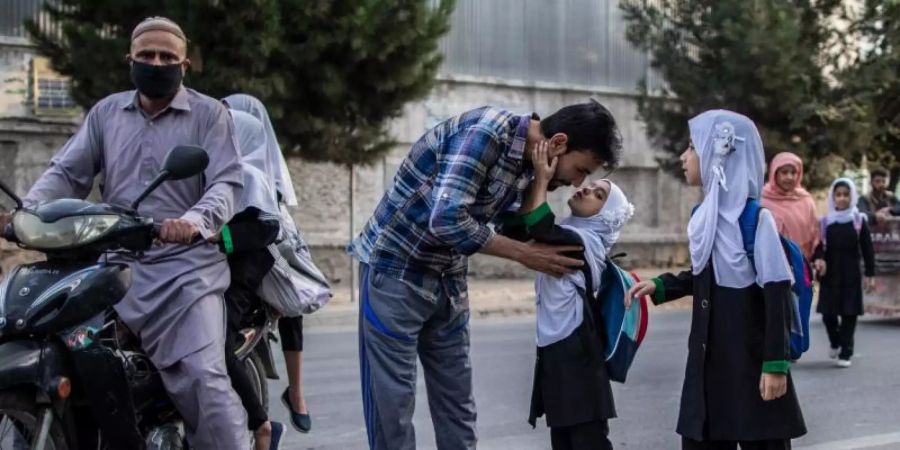 Ein junges afghanisches Mädchen gibt ihrem Vater einen Kuss, bevor sie eine Grundschule in Kabul besucht. (Archivbild). Foto: Oliver Weiken/dpa