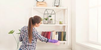 Frau putzt und organisiert ein Regal
