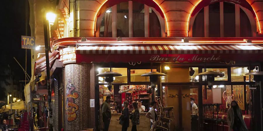 Ein Kellner räumt die Terrasse eines Restaurants vor der nächtlichen Ausgangssperre gegen die Ausbreitung des Coronavirus. Foto: Francois Mori/AP/dpa