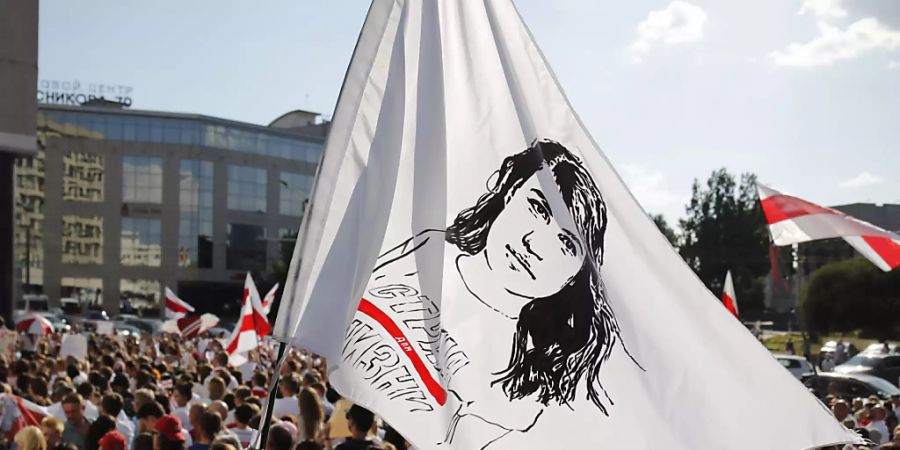 Ein Demonstrant schwenkt eine Flagge mit dem Gesicht der belarussischen Präsidentenkandidatin Tichanowskaja. Foto: Dmitri Lovetsky/AP/dpa