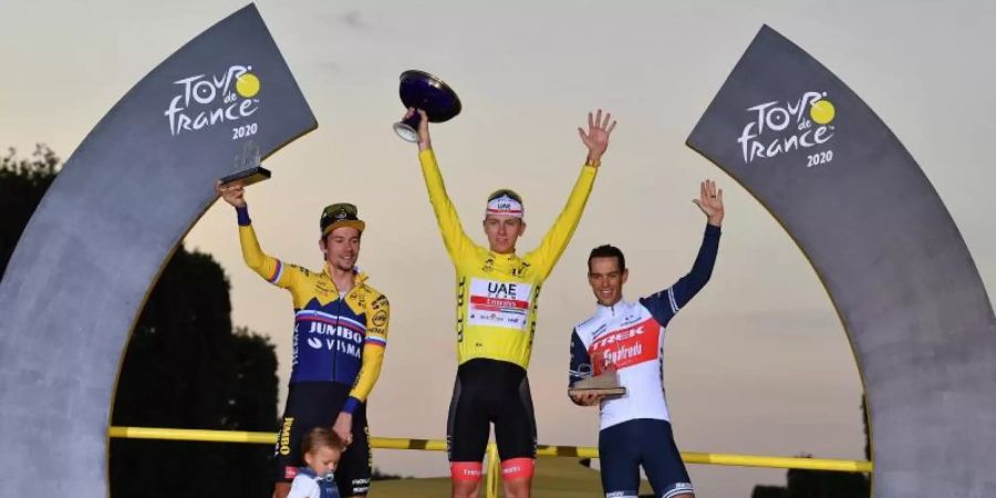 Der Zweitplatzierte Primoz Roglic (l-r) (mit seinem Sohn Lev), Tour-Sieger Tadej Pogacar und der Drittplatzierte Richie Porte feiern auf dem Podium. Foto: David Stockman/BELGA/dpa