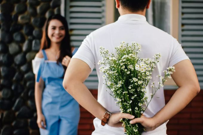 Kleine Aufmerksamkeiten werten den Alltag auf. Mann schenkt Frau Blumen