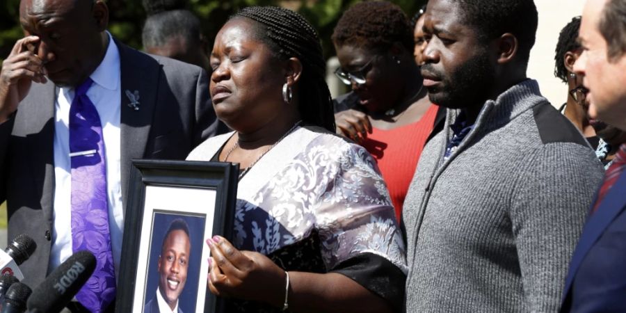 Caroline Ouko mit einem Porträt ihres getöteten Sohnes Irvo Otieno. Neben ihr stehen ihre Anwälte und ihr älterer Sohn Leon Ochieng. Foto: Daniel Sangjib Min/Richmond Times-Dispatch/AP/dpa - ACHTUNG: Nur zur redaktionellen Verwendung und nur mit vollständiger Nennung des vorstehenden Credits