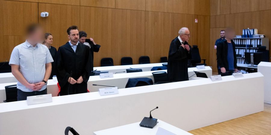 Im Hochsicherheitsgerichtssaal vom Landgericht München II stehen die zwei wegen Mordes angeklagten Männer (l und r) neben ihren Rechtsanwälten. Heute könnte das Urteil fallen.