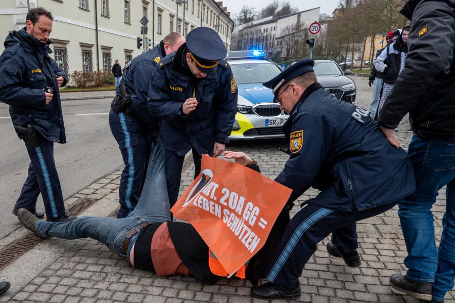 Die Polizei zerrt einen «Klima-Kleber» in Passau von der Strasse.