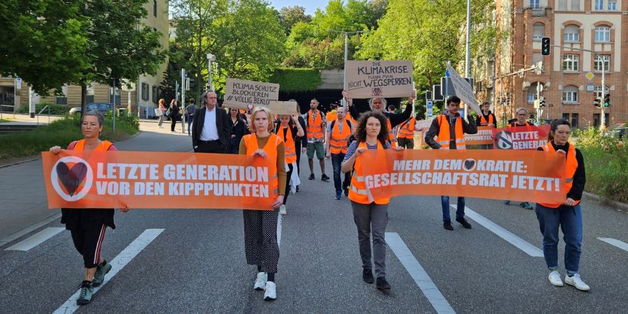 Aktivistinnen und Unterstützer der Gruppierung Letzte Generation demonstrieren in Stuttgart mit Transparenten.