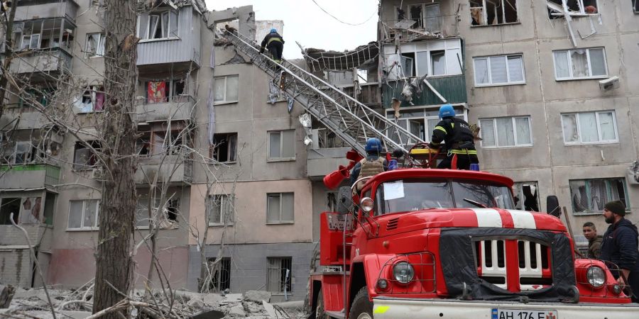 Feuerwehrleute arbeiten daran, ein Feuer zu löschen, während sie nach einem Raketenangriff nach möglichen Opfern suchen.