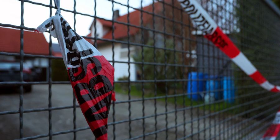 Ein Absperrband der Polizei hängt am Hoftor des Einfamilienhauses, in dem die Leichen eines Ehepaars entdeckt wurden.
