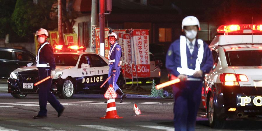 Polizisten stehen Wache auf einer Strasse in der Nähe eines Gebäudes, in dem sich ein Mann verschanzt hat.