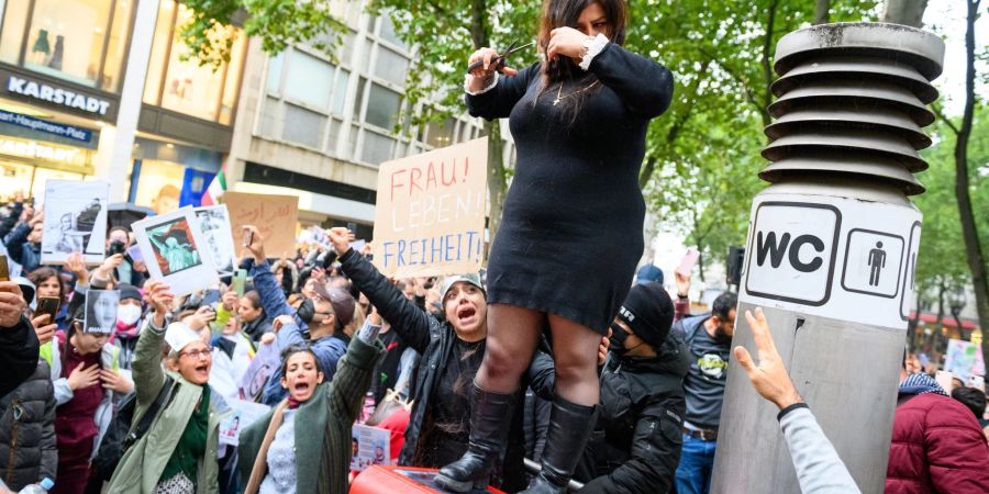 Eine Frau schneidet sich in Hamburg demonstrativ die Haare ab, um sich mit den Frauen im Iran zu solidarisieren.