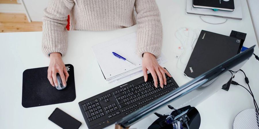 Eine Frau arbeitet vor einem Computer an einem Stehtisch.