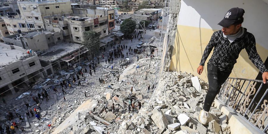 Palästinenser begutachten die massiven Schäden, die ein israelischer Luftangriff auf den Al-Masri-Turm verursacht hat. Foto: Mohammed Talatene/dpa