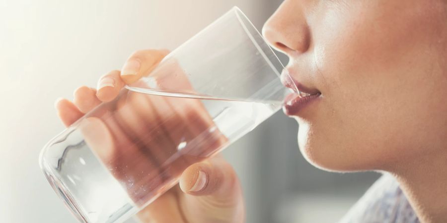 Frau trinkt Wasser aus Wasserglas