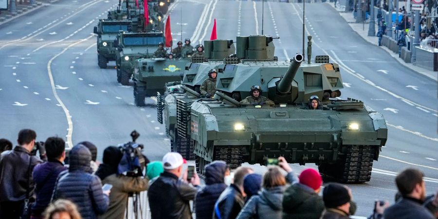 Zuschauer beobachten im Mai 2022, wie ein russischer T-14 Armata-Panzer (im Vordergrund) und andere gepanzerte Fahrzeuge auf der Twerskaja-Strasse in Richtung Roter Platz rollen.