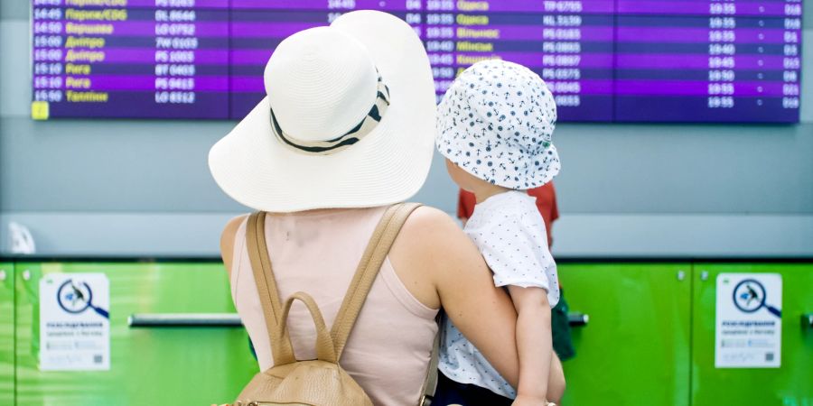 frau mit kind im arm, rückansicht, flughafen