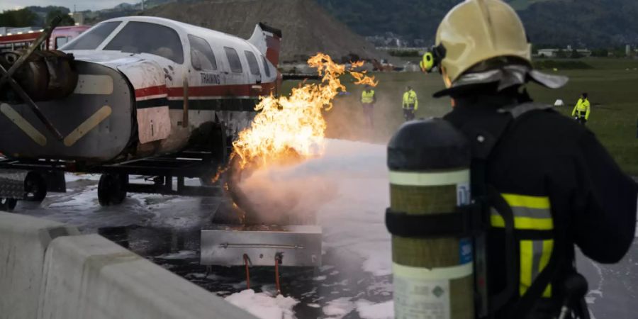 Ein Kleinflugzeug brennt, ein Feuerwehrmann greift ein: Notfallübung auf dem Flugplatz in Thun.