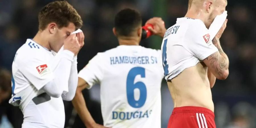 Mats Köhlert (l-r), Douglas Santos und Rick van Drongelen sind fassungslos: Der HSV hat daheim gegen Magdeburg mit 1:2 verloren. Foto: Christian Charisius/dpa